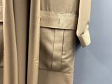 un trench-coat beige accroché à un mur bleu dans une pièce