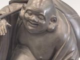 a statue of a laughing buddha holding a stick