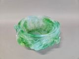 a green glass bowl sitting on top of a white table