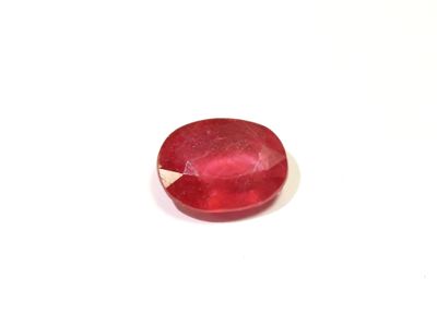 a close up of a red stone on a white surface