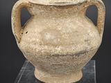 un vase posé sur un socle, sur une surface noire