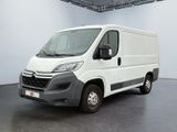 La camionnette blanche est garée dans une grande pièce au sol noir.