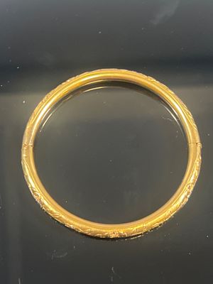 un gros plan d'un bracelet en or sur une surface noire