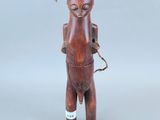 une image représentant une figurine en bois d'un homme portant un panier sur la tête