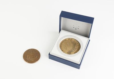 une petite pièce d'or dans une boîte bleue, à côté d'un penny