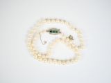 an image of a white pearl necklace with a green clasp