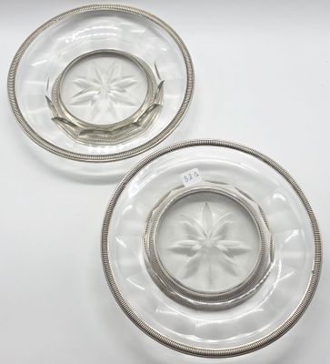 deux assiettes en verre transparent aux bords argentés, posées sur un plateau blanc
