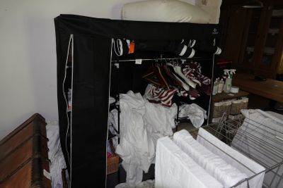 une armoire pleine de vêtements et un lit recouvert d'un couvre-lit noir