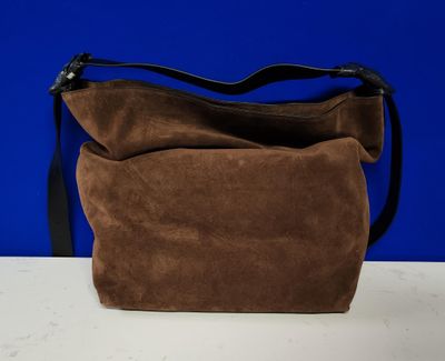 un sac à main en daim marron posé sur une table blanche
