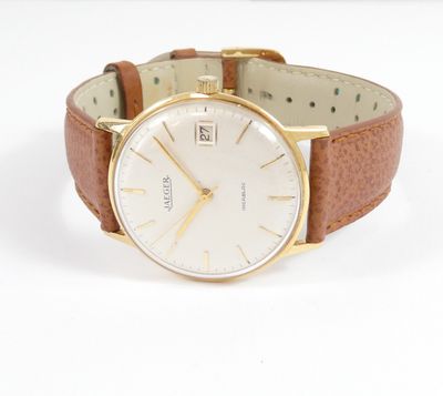 a close up of a watch on a white surface with a brown strap