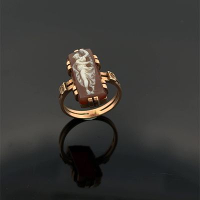 une bague en or ornée d'une incrustation représentant une femme tenant un enfant dans ses bras