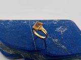 une image représentant une bague en or sertie d'une pierre jaune posée sur une pierre bleue