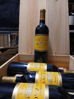 Plusieurs bouteilles de vin sont posées dans une caisse en bois sur une table