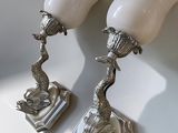 paire de lampes plaquées argent avec des abat-jours blancs, posées sur un support blanc