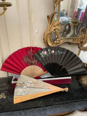 un éventail rouge et noir posé sur une table à côté d'un miroir
