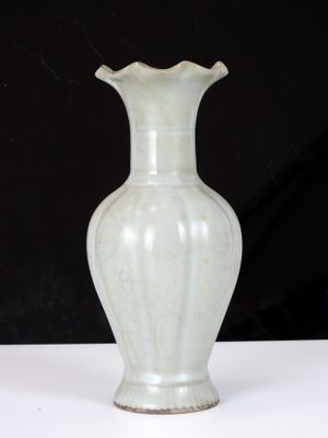 un vase blanc posé sur une table sur fond noir
