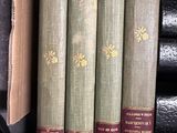 three old books are stacked on a shelf in a library
