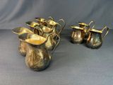 a group of silver pitchers and cups on a table