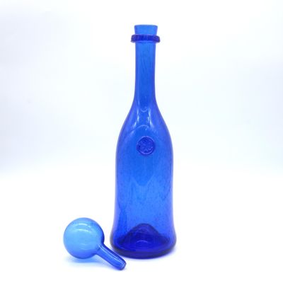a blue glass bottle and a blue glass ball on a white surface