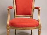 a red chair with gold trim and a red upholstered seat