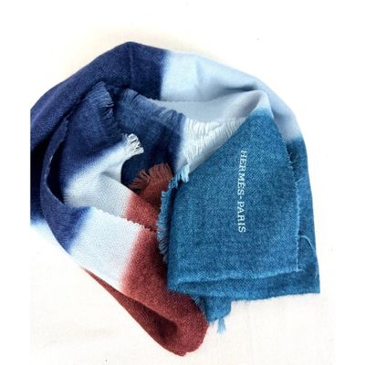 une écharpe bleue et rouge et une écharpe bleue et blanche posées sur une surface blanche