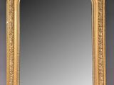 a gold framed mirror with ornate design on a grey background
