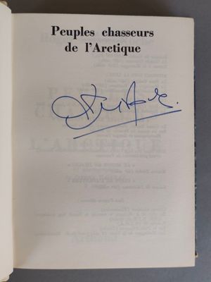 un livre ouvert, sur lequel figure une signature manuscrite, posé sur une table
