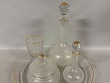 une assiette en verre sur laquelle sont posés une carafe en verre et un verre