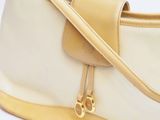 a white purse with a gold handle on a white surface