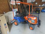un petit tracteur bleu et orange garé dans un garage