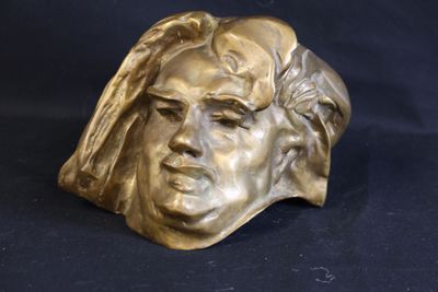 bronze sculpture of a man ' s face on a black background