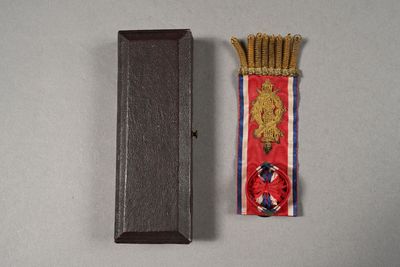 une petite boîte en bois ornée d'un ruban rouge et d'un ruban rouge et blanc