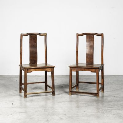two wooden chairs sitting next to each other on a cement floor