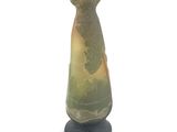 a green and yellow vase sitting on top of a black stand