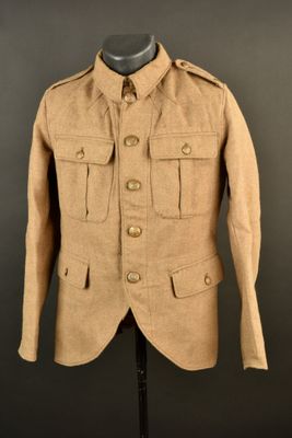 une vieille veste militaire posée sur un mannequin, devant un fond noir