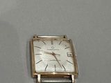 une petite montre carrée en argent posée sur une table