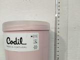 a pink container with a label on it next to a ruler