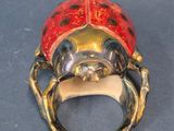 silver ring with a red ladybug on it sitting on a blue surface