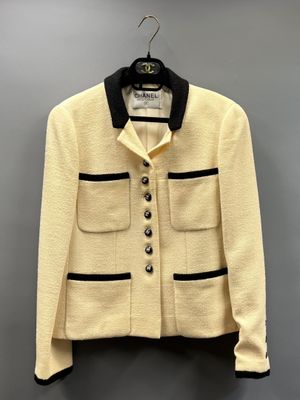 une veste blanche à bordures noires suspendue à un cintre