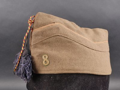 le chapeau est de couleur beige et est orné d'un pompon
