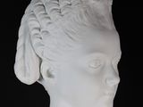 a white statue of a woman with a feather on her head