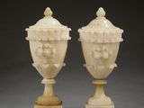 pair of carved ivory vases on pedestals on a gray background
