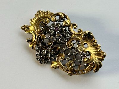 une broche en or posée sur une surface blanche, avec un fond blanc
