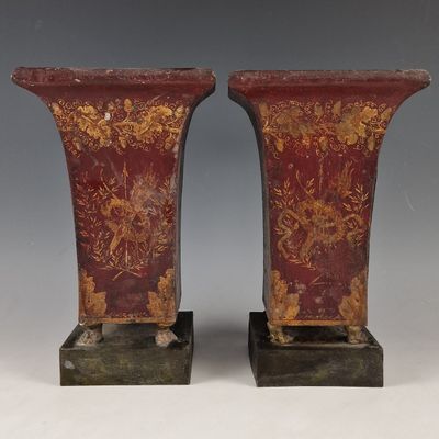 une paire de vases rouges et dorés posés sur un socle en bois
