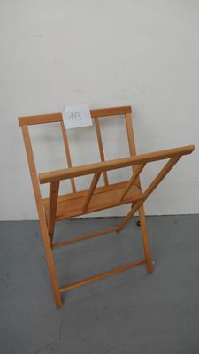 une chaise pliante en bois sur laquelle est accrochée une pancarte