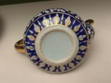 a blue and gold cup and saucer sitting on a table
