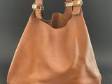 a tan leather handbag on a black background
