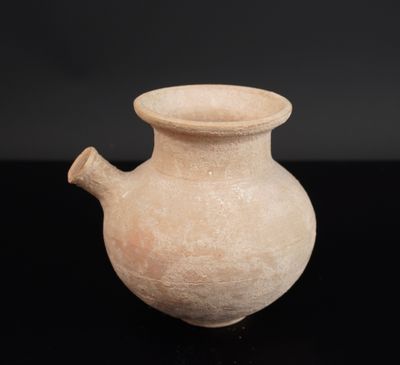 un vieux vase posé sur une table noire, près d'un mur noir