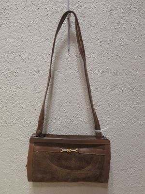 un sac à main en cuir marron accroché à un mur blanc dans une pièce