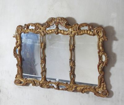 a gold mirror hanging on the wall next to a white wall
